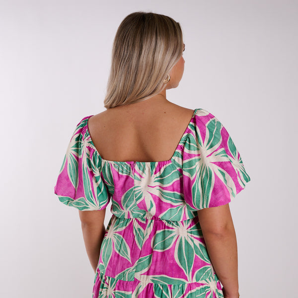 Woman wearing a pink and green floral dress against a white background