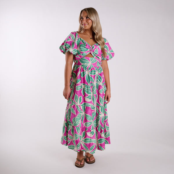 Woman wearing a pink and green floral dress on a white background