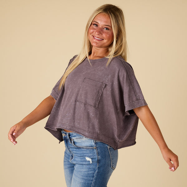  Woman wearing a oversized charcoal grey t-shirt and blue jeans on a beige background