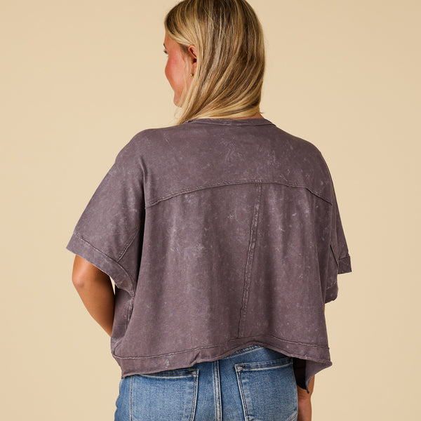  Person wearing a charcoal distressed shirt and blue jeans on a beige background