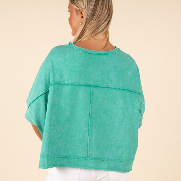  Very J Boxy Pocket Short Sleeve Crop Top, sizes S-L, color green. Back view of a woman wearing a green cropped t-shirt showing seam detailing and loose short sleeves.