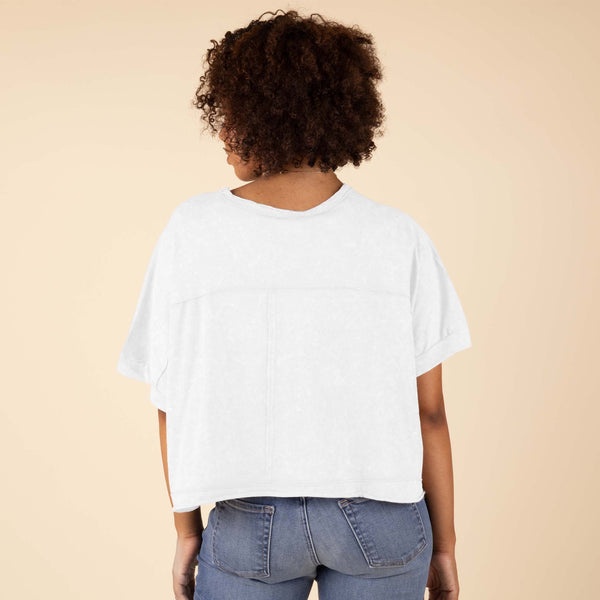  Very J Boxy Top in Taupe on a woman posing in front of a neutral background. Back view showing the relaxed silhouette of the style.