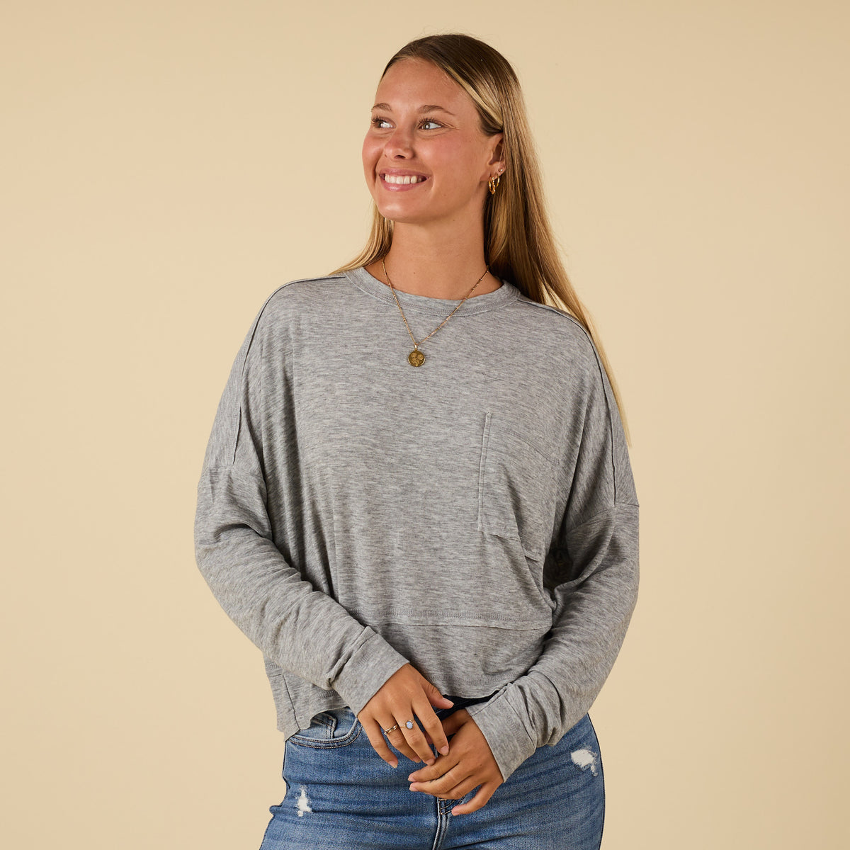 Woman in grey long sleeve relaxed pocket top with front pocket.