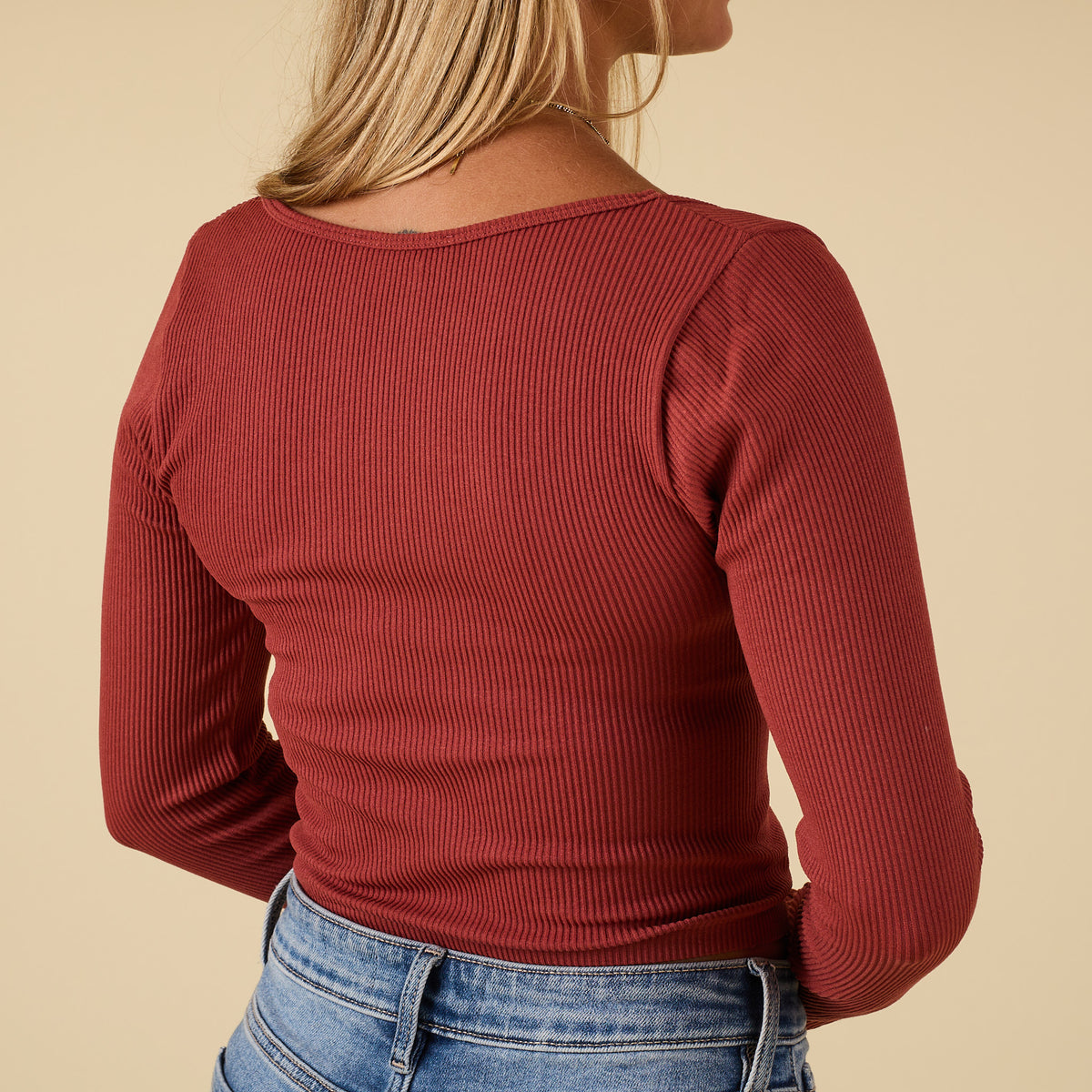 Back view of rust ribbed long sleeve scoop neck top with fitted shape and ribbed fabric detail.