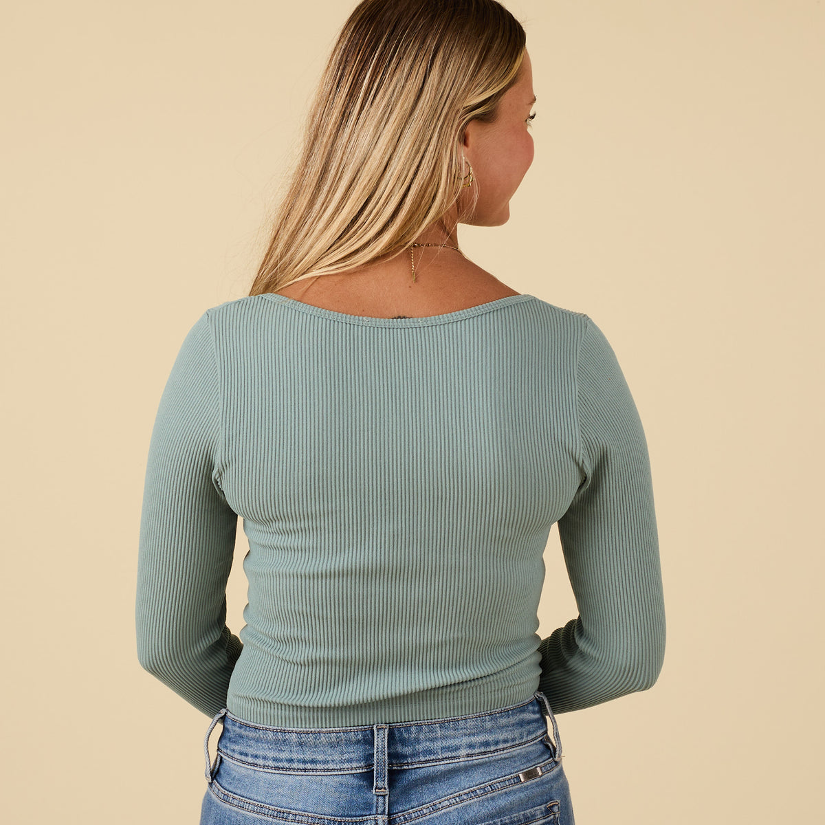 Back view of sage ribbed long sleeve scoop neck top with fitted silhouette and cropped hemline.