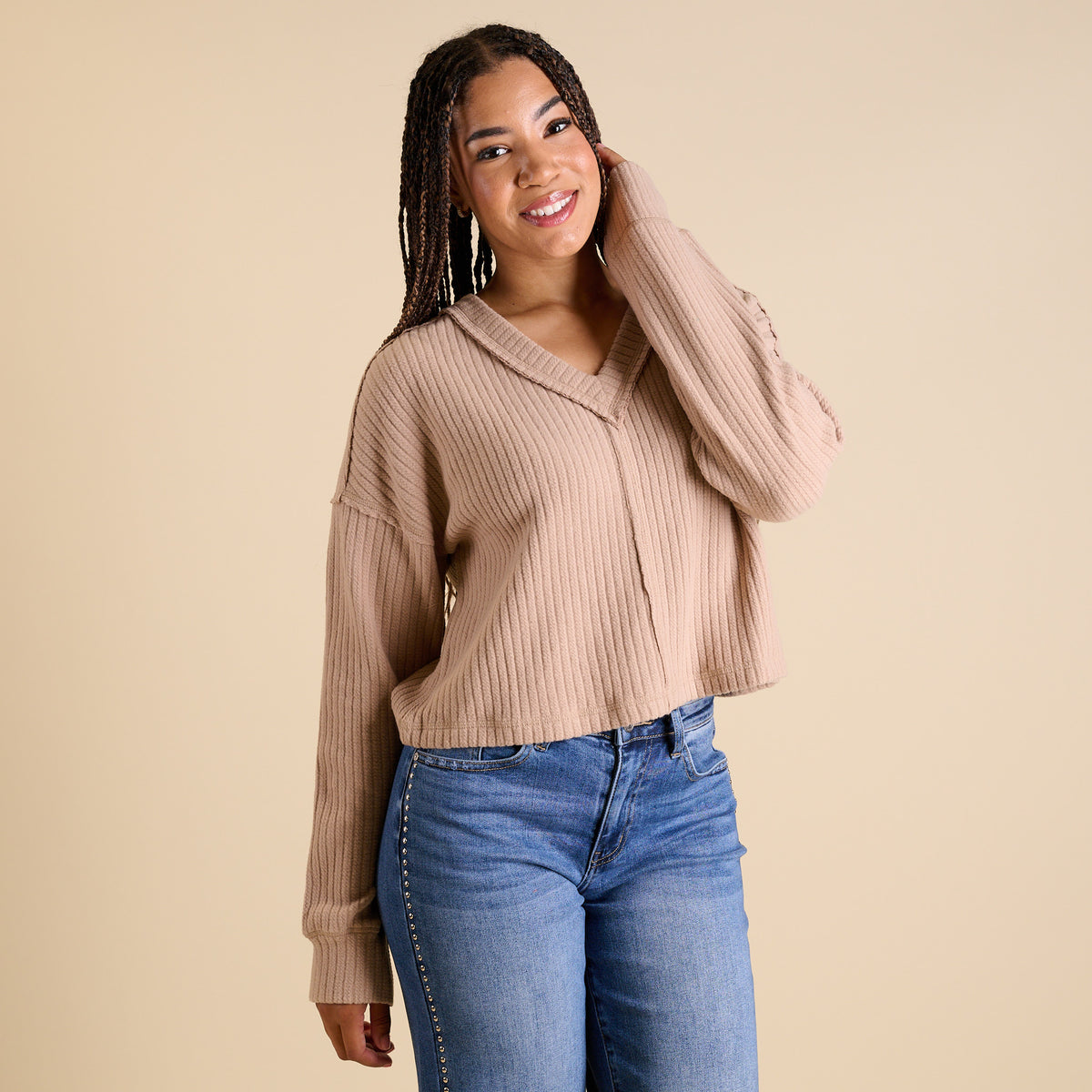 Model wearing mocha ribbed V-neck cropped sweater with long sleeves and relaxed fit.
