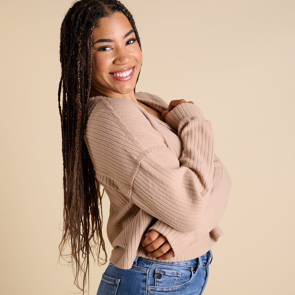 Model wearing mocha ribbed V-neck cropped sweater with long sleeves and relaxed fit.