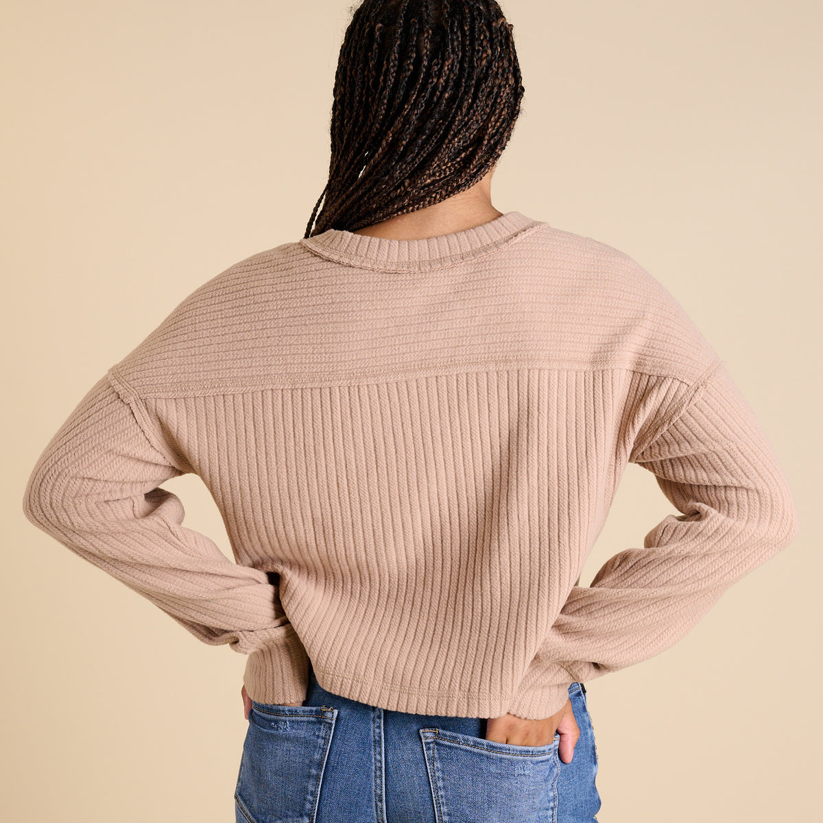 Model wearing mocha ribbed V-neck cropped sweater with long sleeves and relaxed fit.