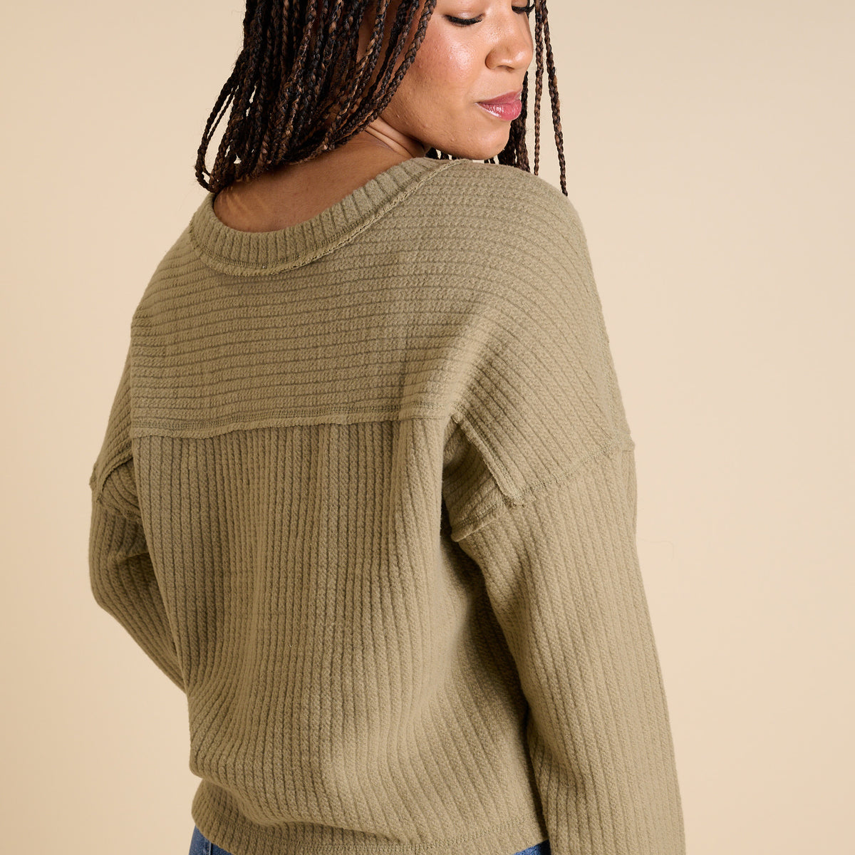 Model wearing olive ribbed V-neck cropped sweater with long sleeves and relaxed fit.