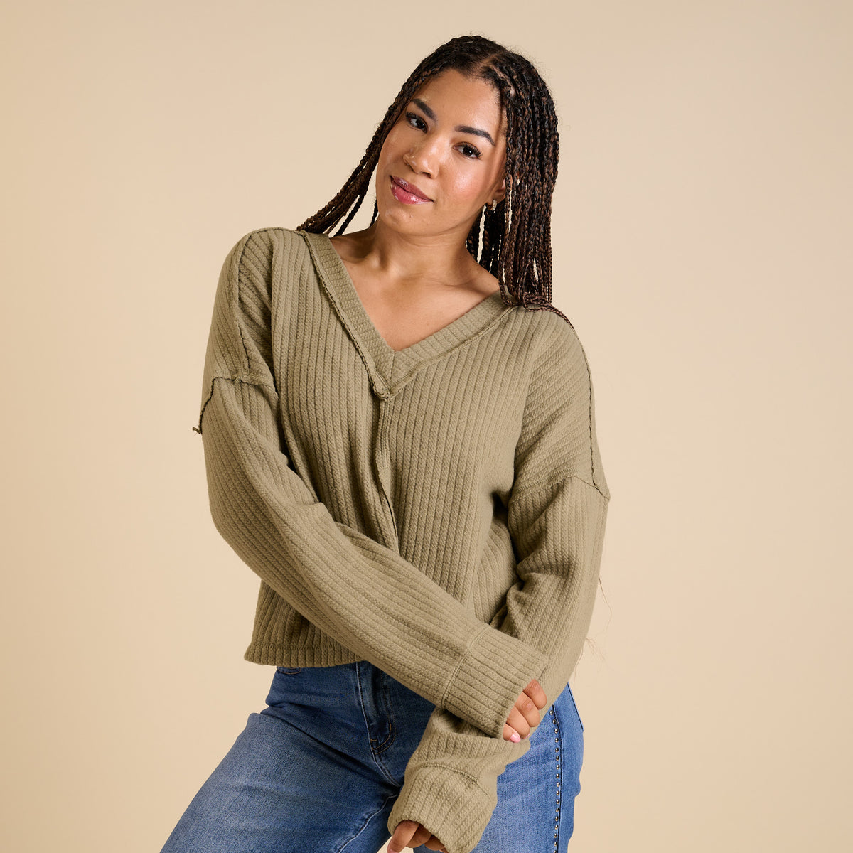 Model wearing olive ribbed V-neck cropped sweater with long sleeves and relaxed fit.