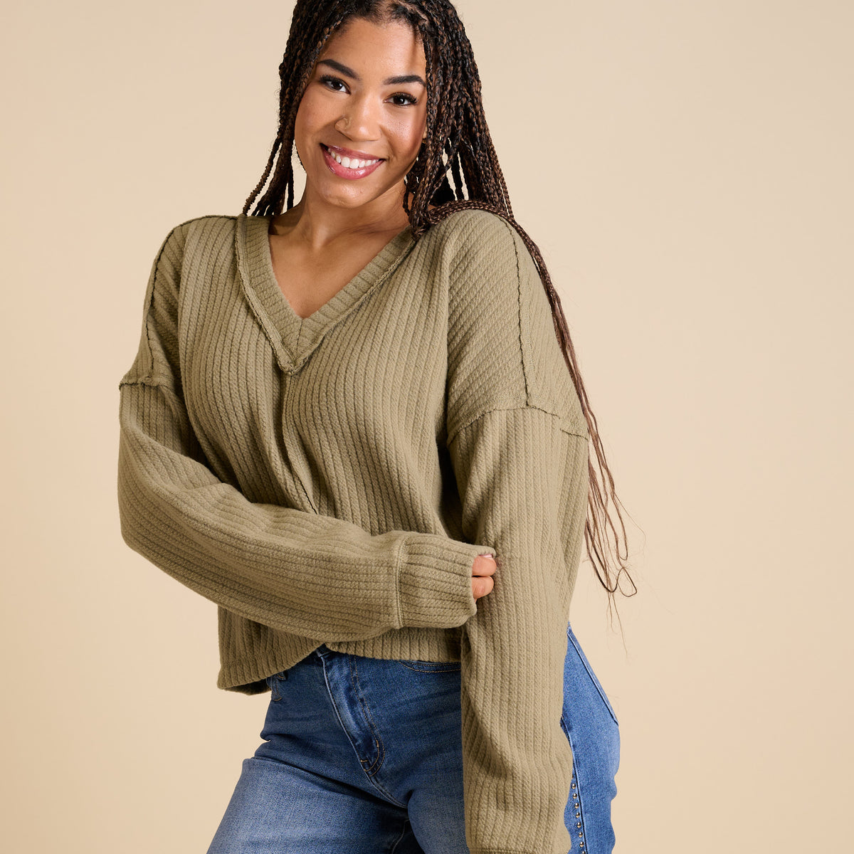 Model wearing olive ribbed V-neck cropped sweater with long sleeves and relaxed fit.