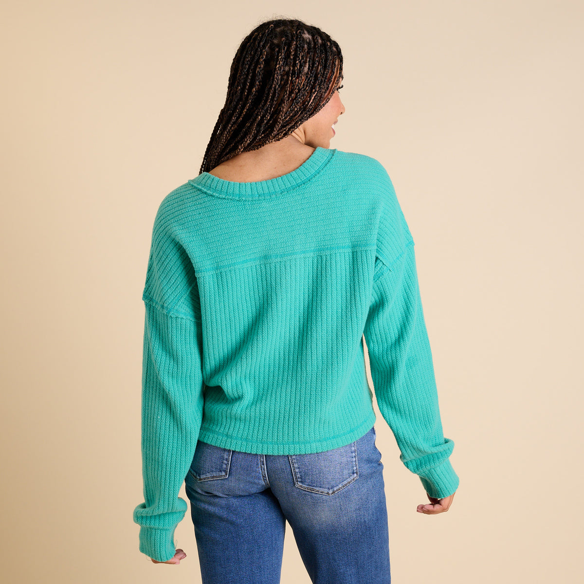 Model wearing seafoam ribbed V-neck cropped sweater with long sleeves and relaxed fit.