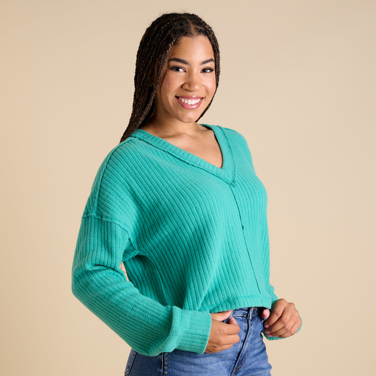 Model wearing seafoam ribbed V-neck cropped sweater with long sleeves and relaxed fit.