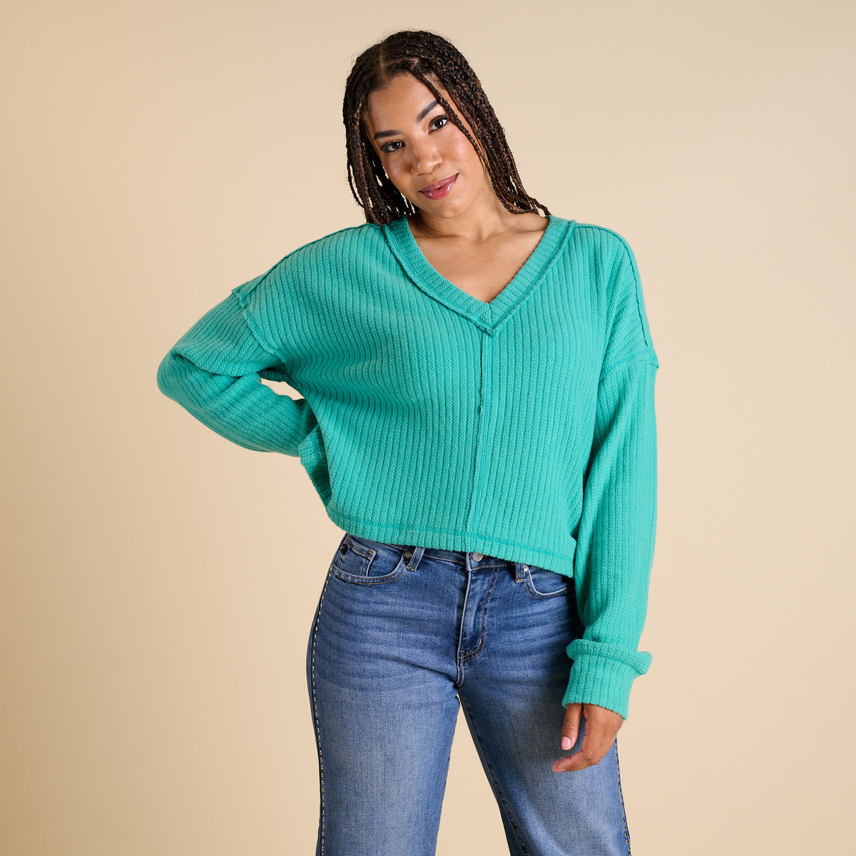 Model wearing seafoam ribbed V-neck cropped sweater with long sleeves and relaxed fit.