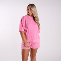 Women’s pink oversized short sleeve lounge top and matching shorts set with relaxed fit and elastic waistband, shown on model against a neutral studio background.