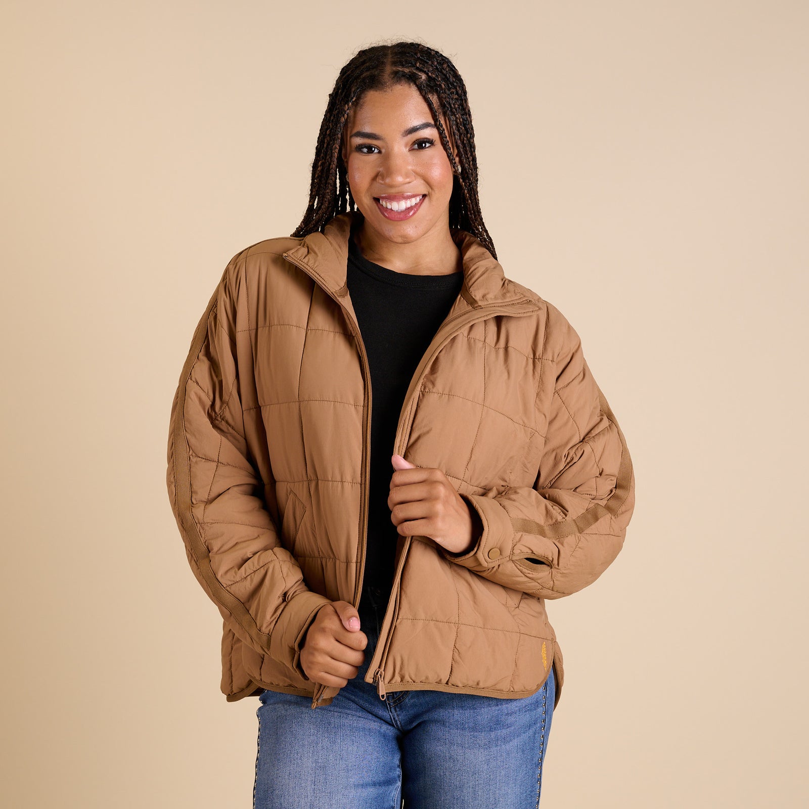 Woman wearing a brown quilted jacket on a beige background