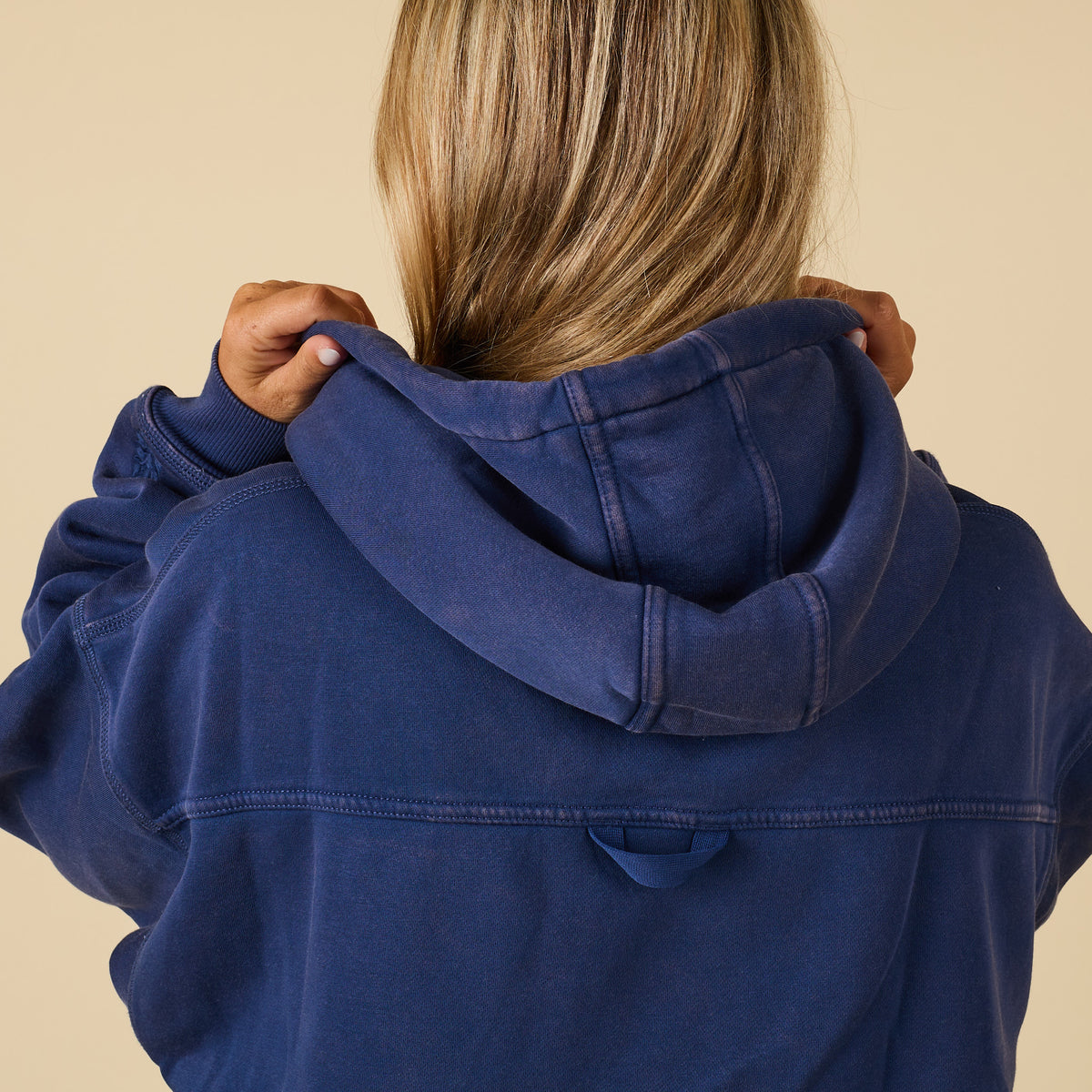 Close-up back view of navy hoodie hood and seams with relaxed oversized fit.