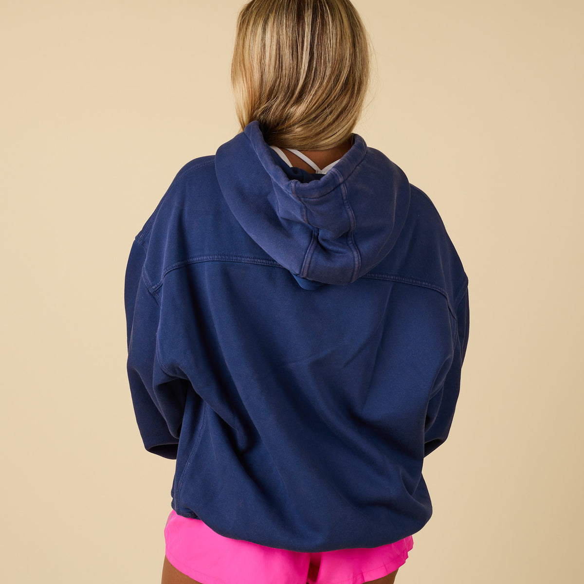 Back view of oversized navy hoodie paired with bright pink shorts.