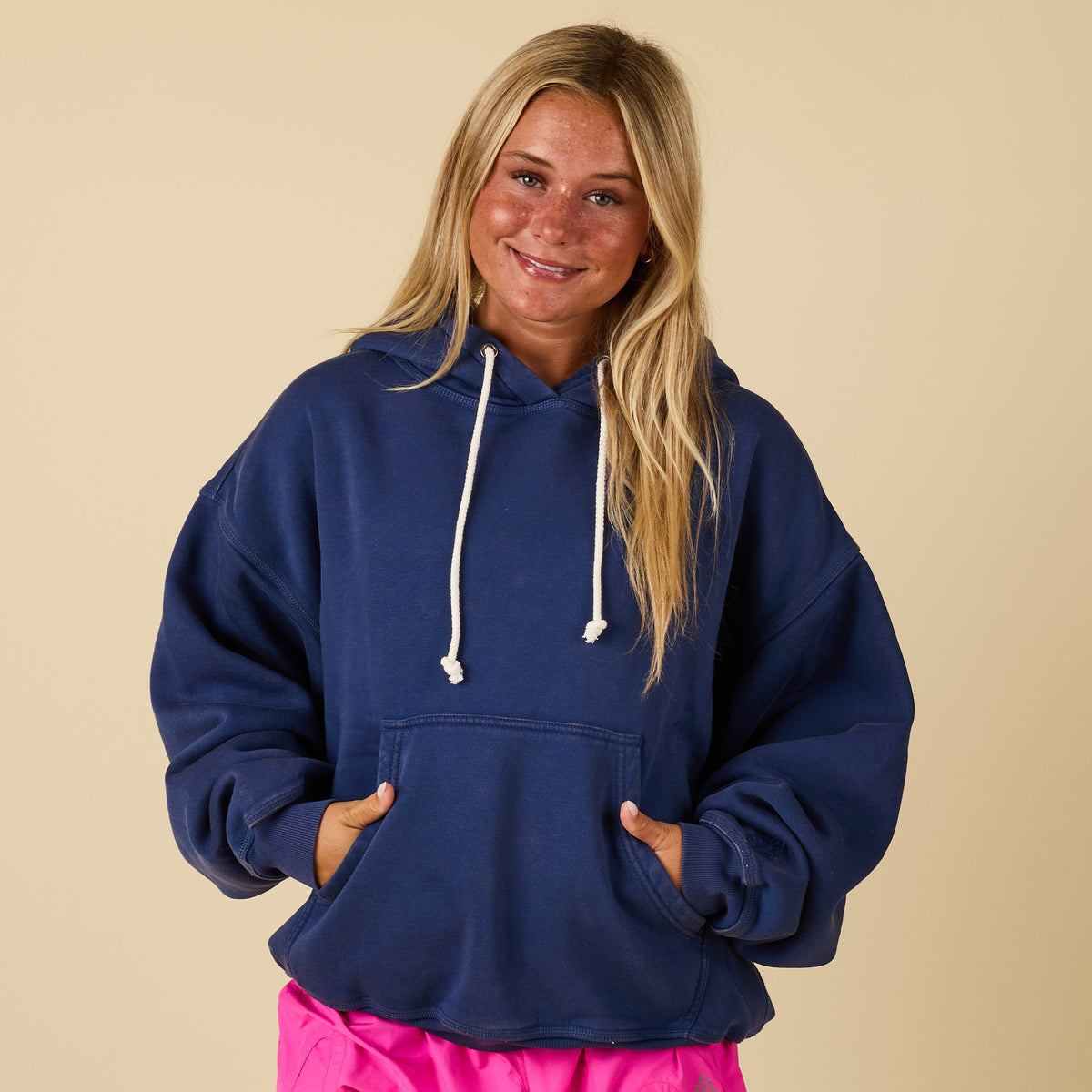 Front view of oversized navy hoodie with white drawstrings and kangaroo pocket, paired with pink shorts.