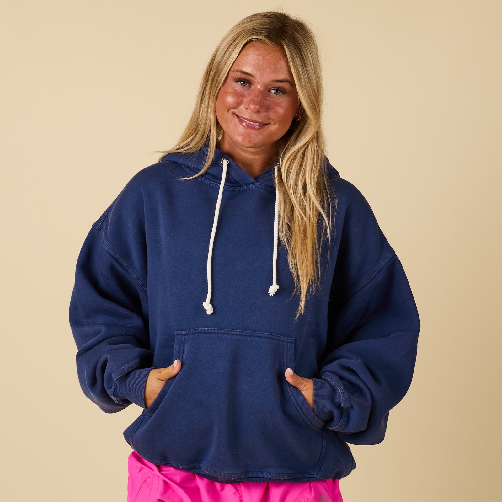 Front view of oversized navy hoodie with white drawstrings and kangaroo pocket, paired with pink shorts.