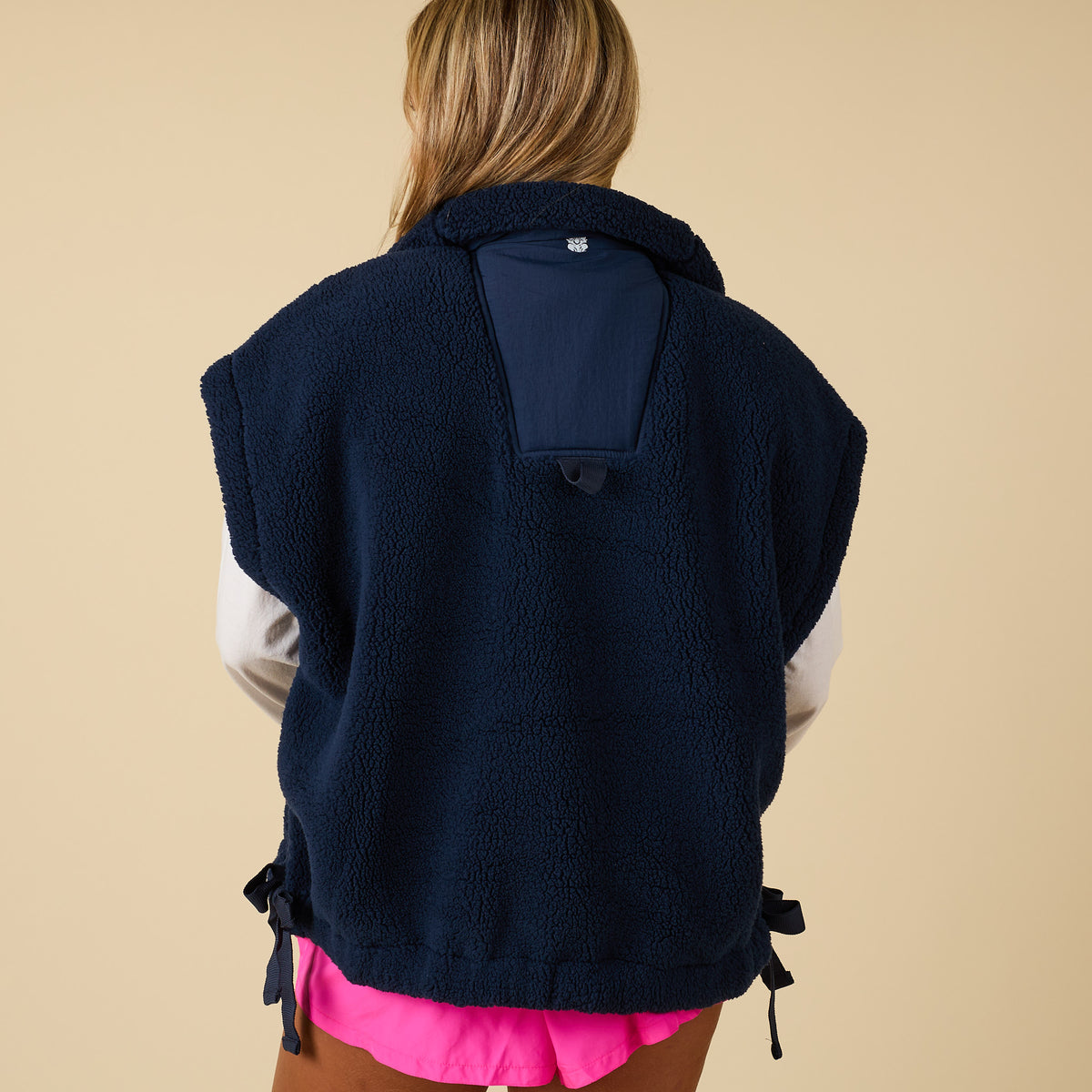 Back view of navy sherpa vest with side ties and back ventilation flap detail.