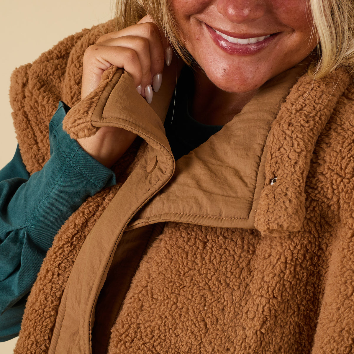 Close-up of collar and snap button detail on brown sherpa vest.