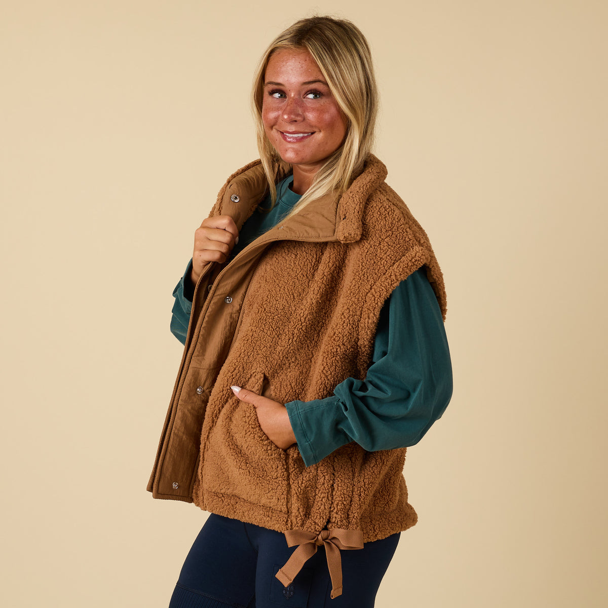 Side view of brown sherpa vest with front pocket and tied side detail.