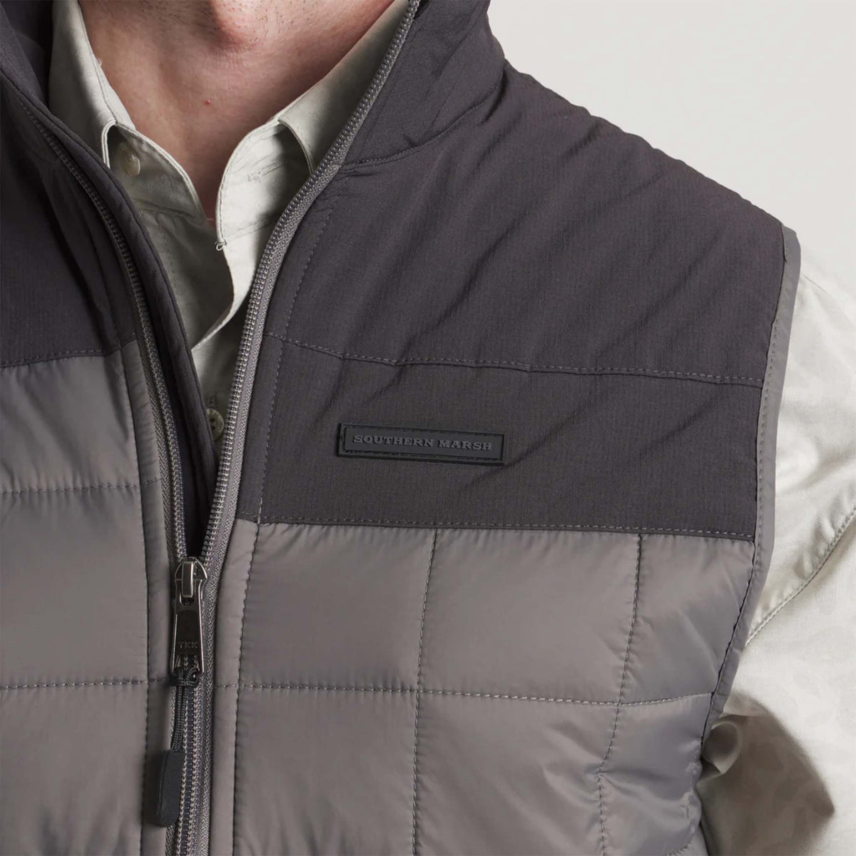 Gray quilted vest with a brand label on a neutral background