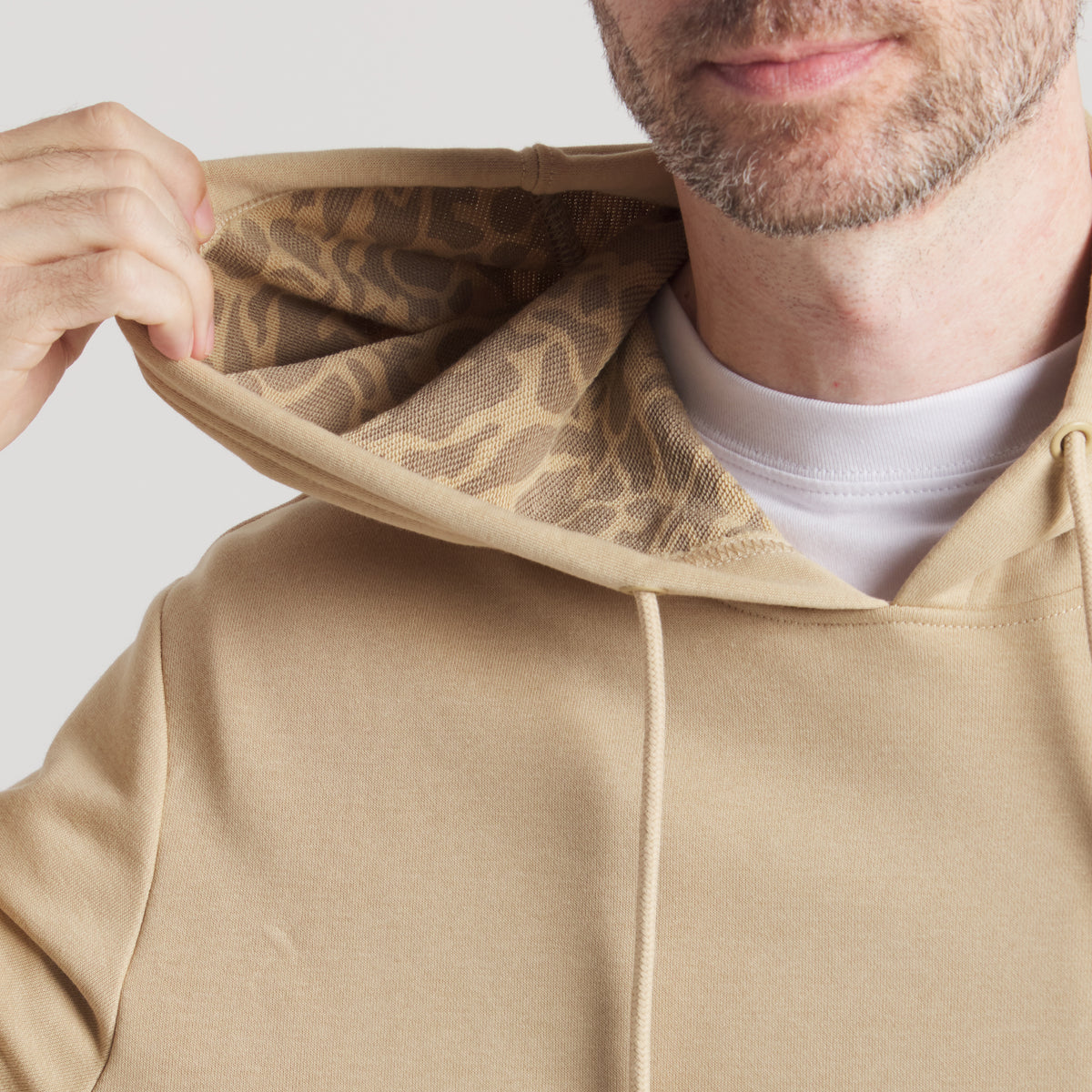 Tan hoodie with kangaroo pocket and drawstrings, shown with hood lifted to reveal tonal animal print lining.