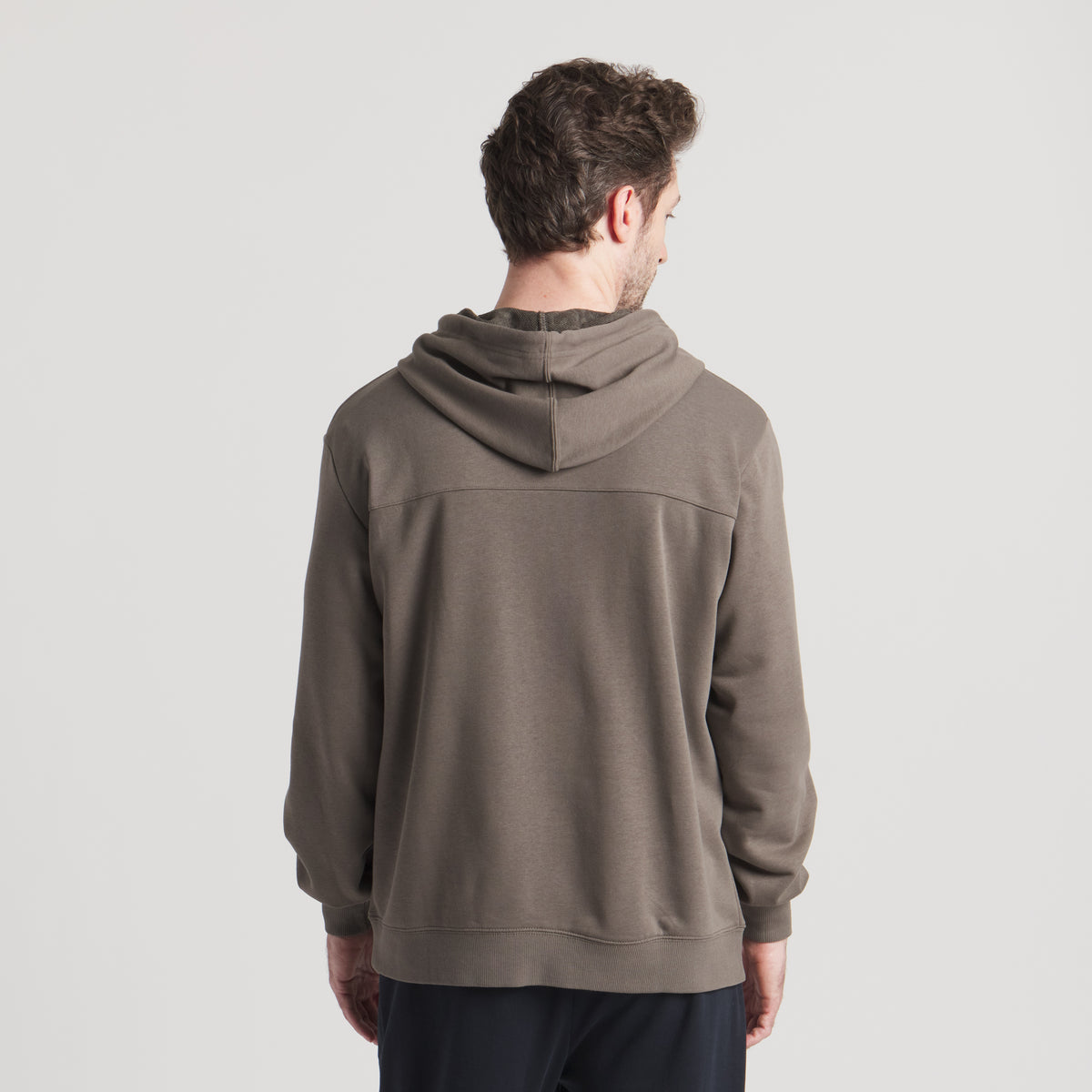 Back view of model wearing dark brown hoodie with hood down and relaxed fit.