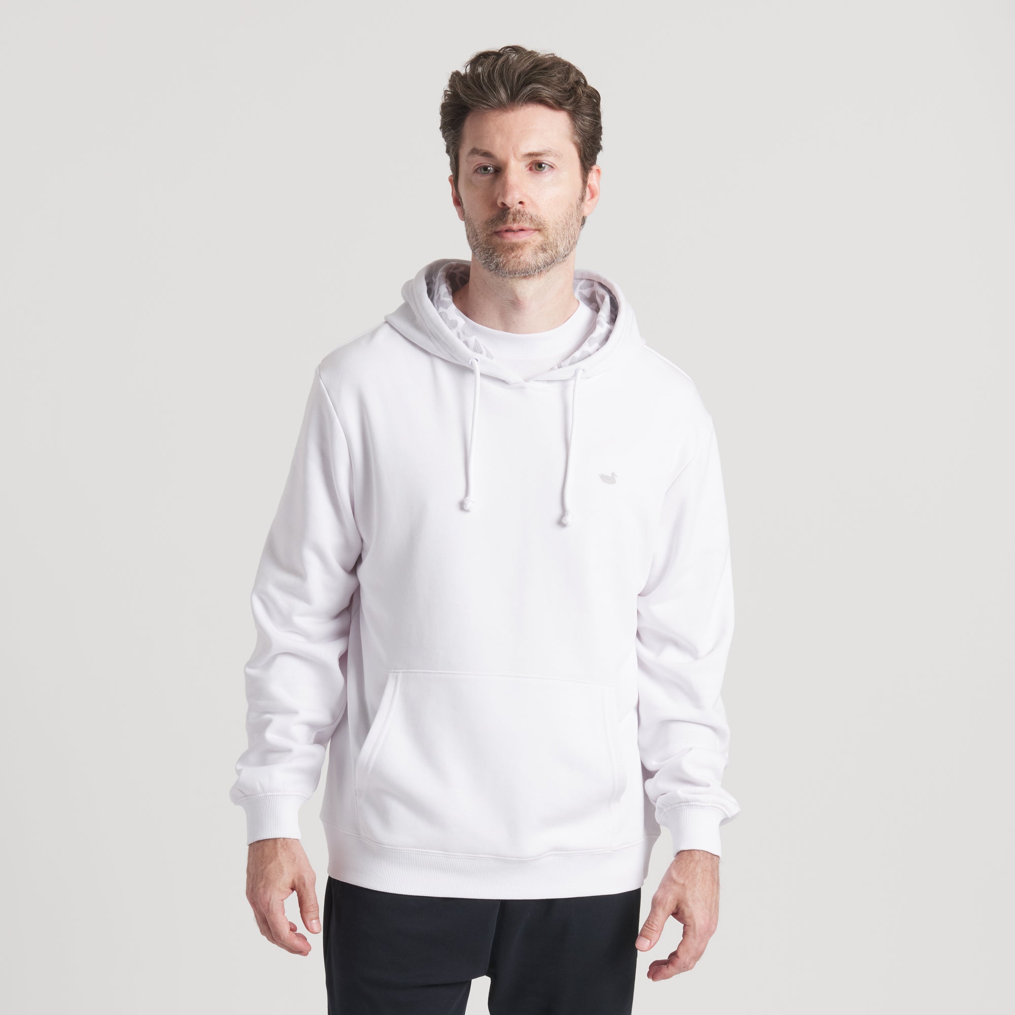 Front view of model wearing white hoodie with kangaroo pocket and drawstrings.