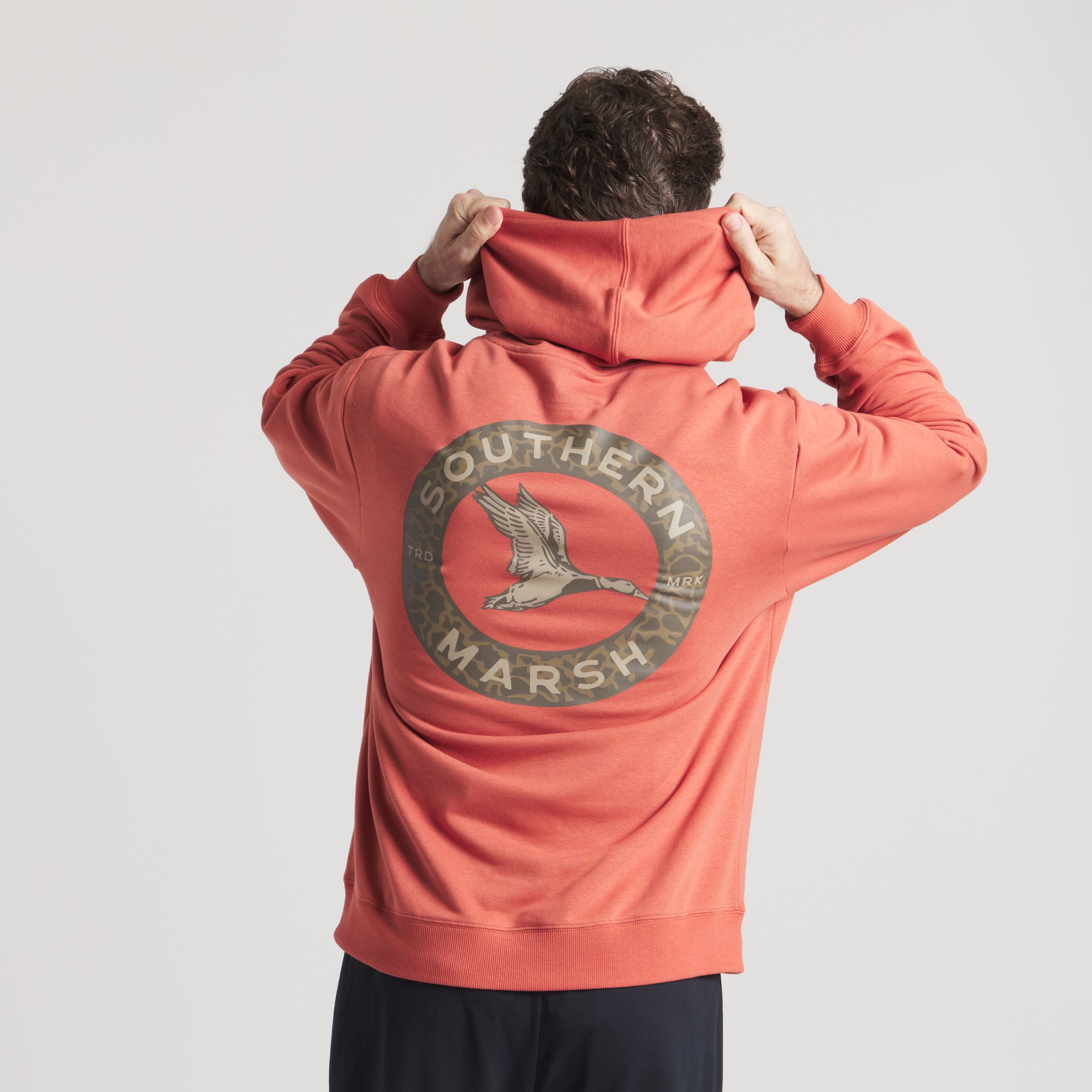 Person wearing a red hoodie with 'Southern Marsh' logo on the back against a light gray background