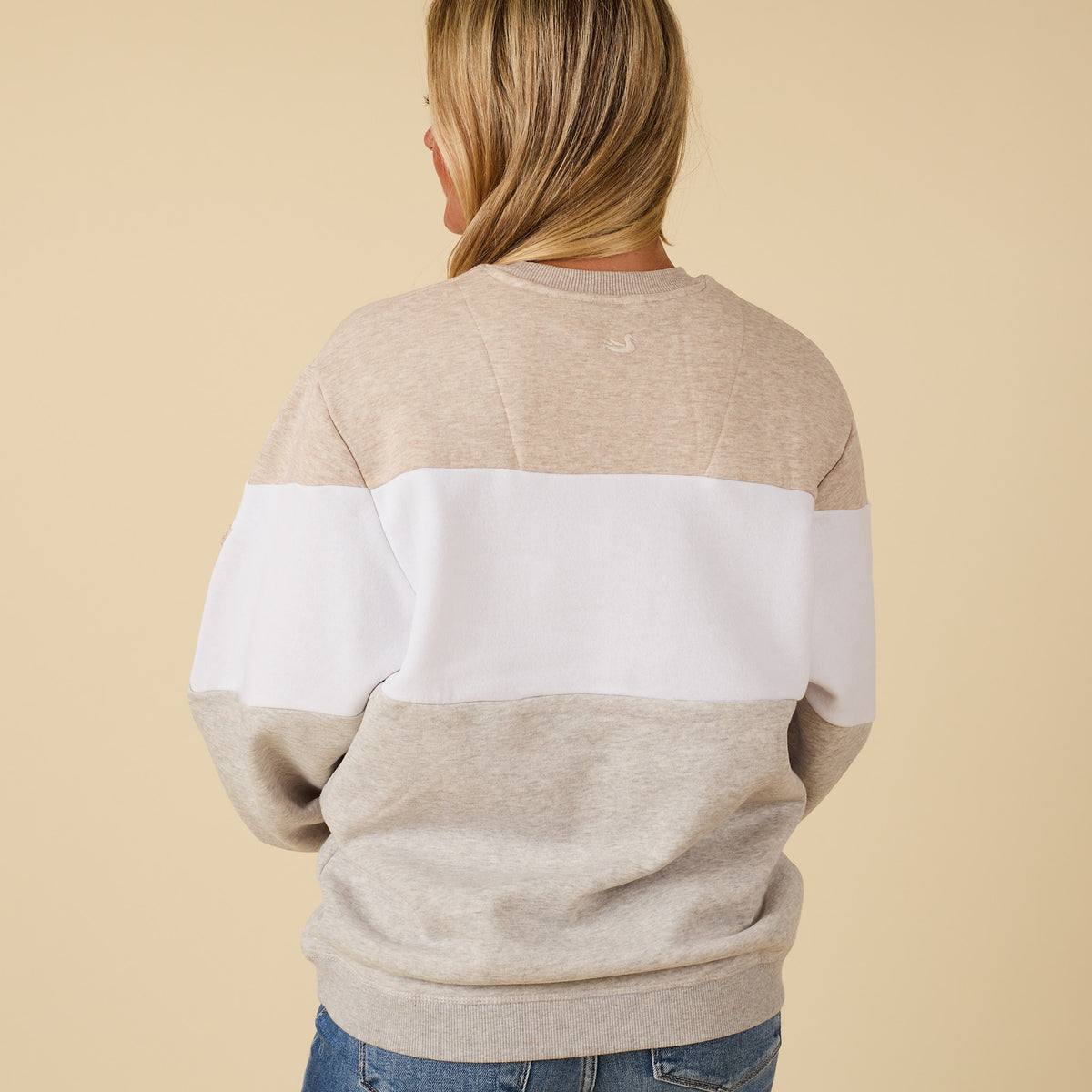 Person wearing a beige and white striped sweater on a beige background