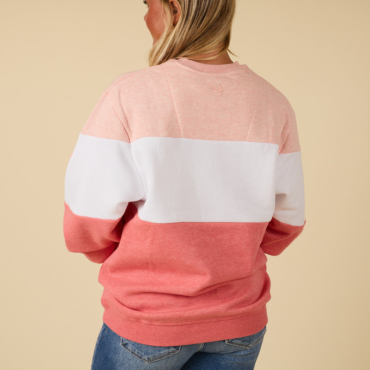 Person wearing a pink and white striped sweater on a beige background