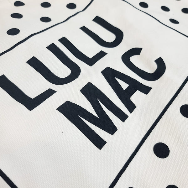  White canvas tote bag with black polka dot pattern and 'LULU MAC' branding on a white background