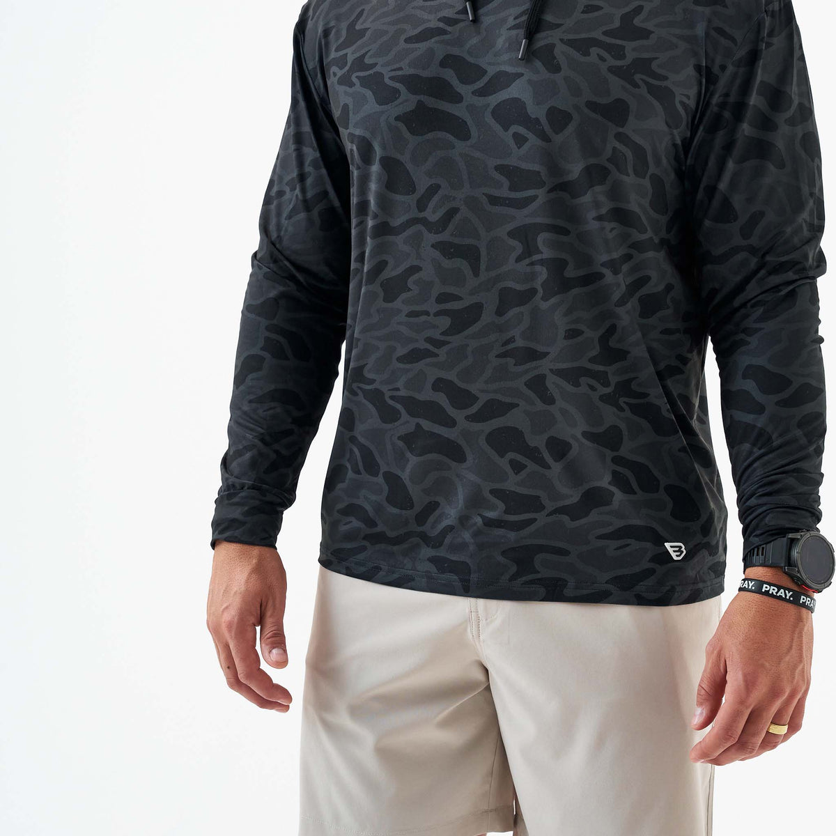 Person wearing a black camouflage long-sleeve shirt on a white background