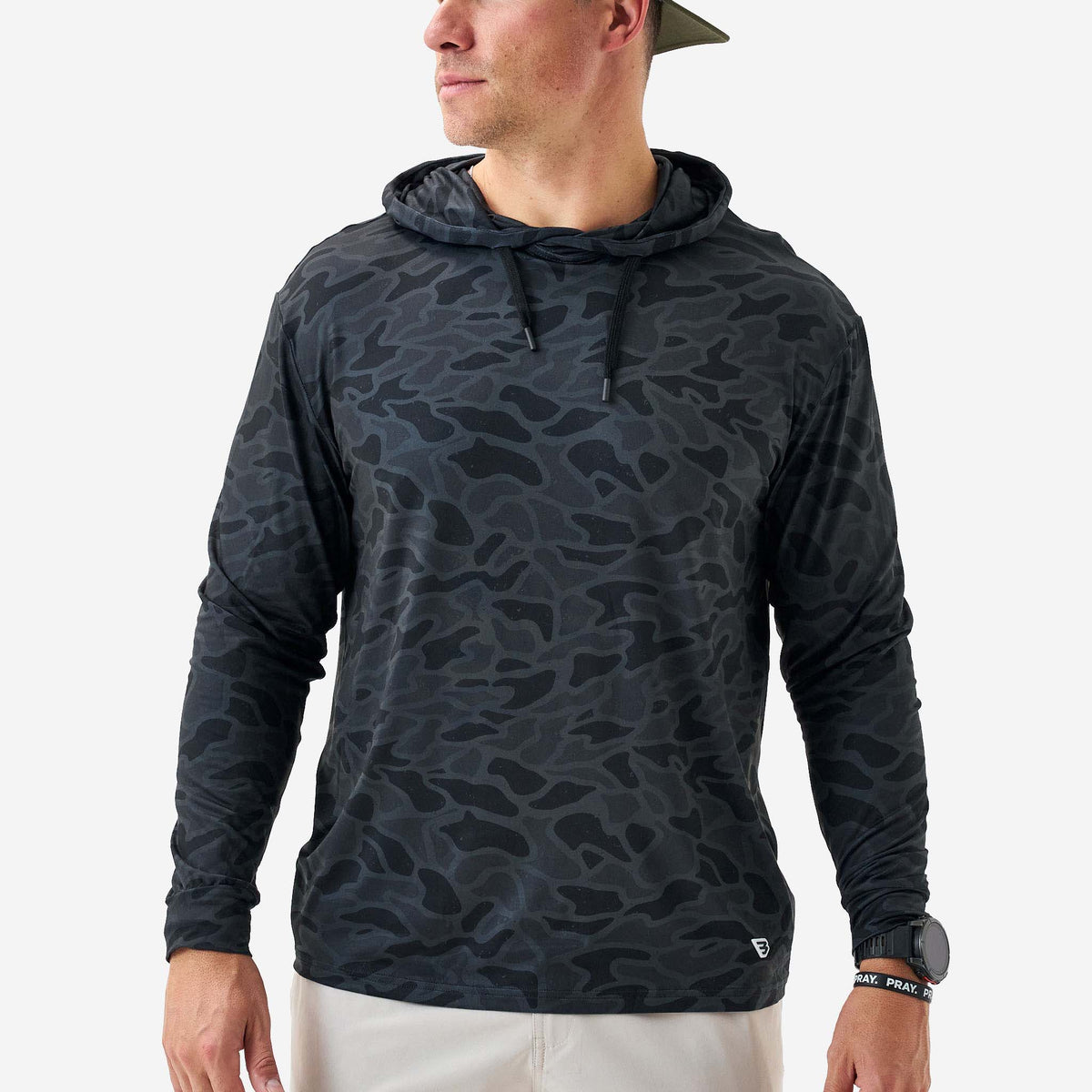 Person wearing a black camouflage hoodie on a white background