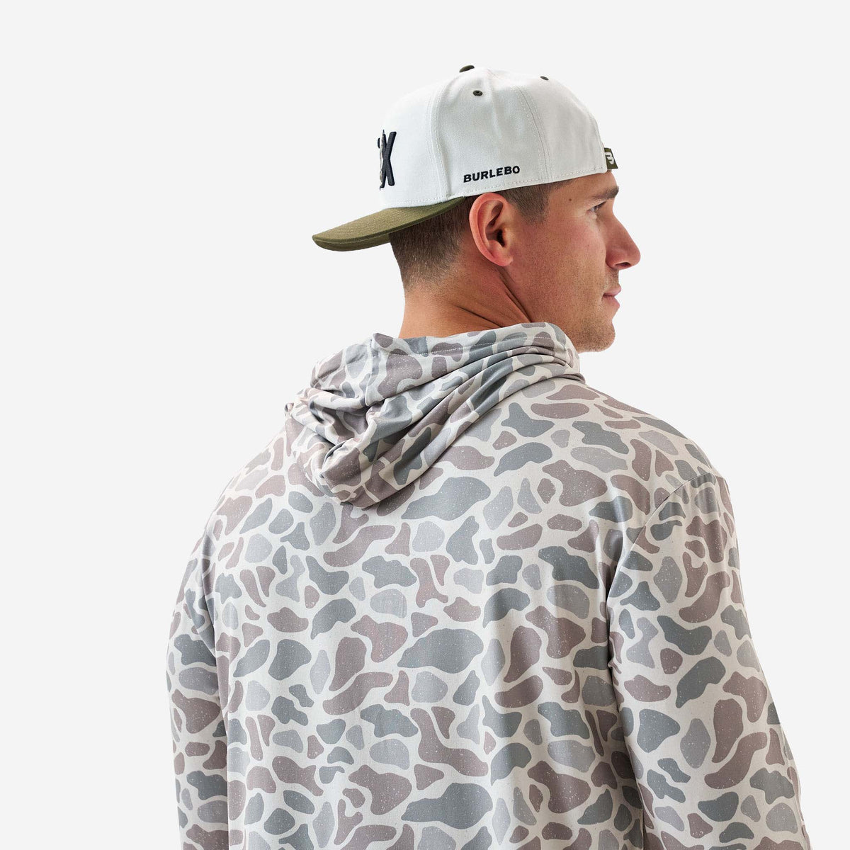 Man wearing a camouflage-patterned hoodie and a cap with 'Burlebo' branding on a white background