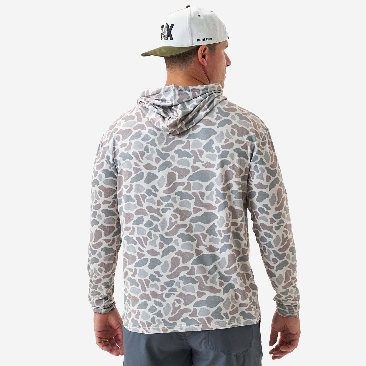 Person wearing a camouflage hoodie and cap on a white background
