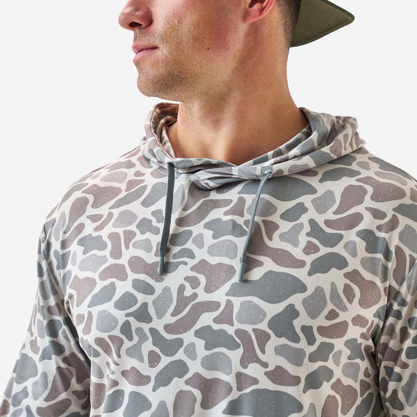 Person wearing a camouflage-patterned hoodie on a white background
