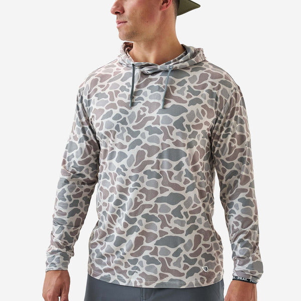 Person wearing a camouflage-patterned hoodie on a white background