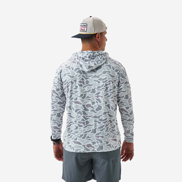 Man wearing a camouflage hoodie and gray shorts on a white background