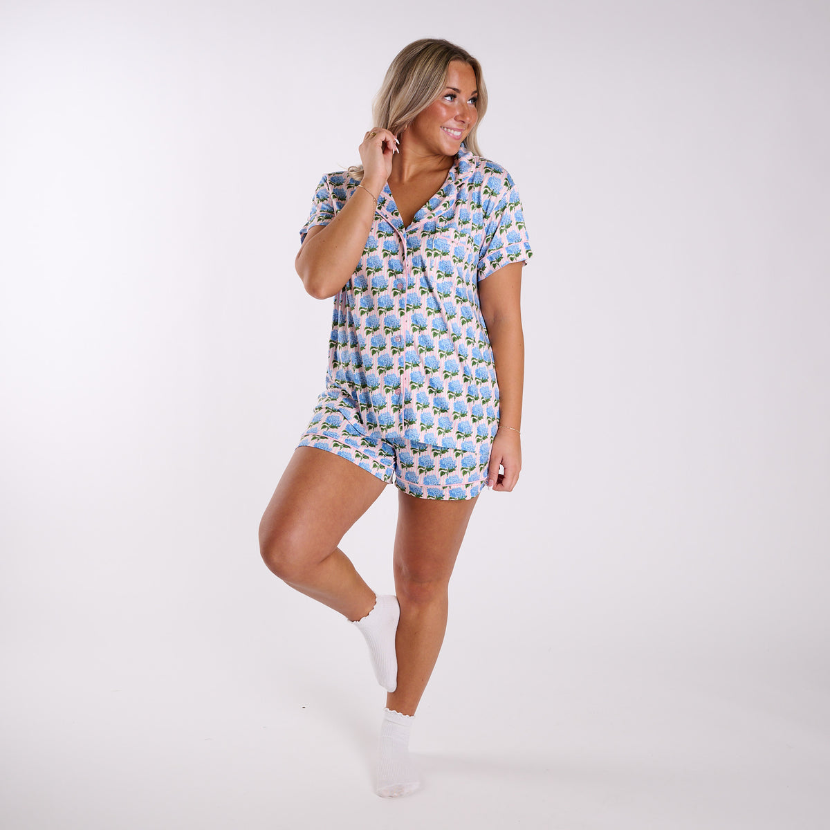 Pink hydrangea print pajama set full body view showing relaxed fit and short sleeve top with contrast piping.
