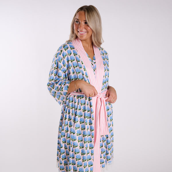 Pink hydrangea print robe front view with blue floral pattern, striped trim, and tie waist detail.