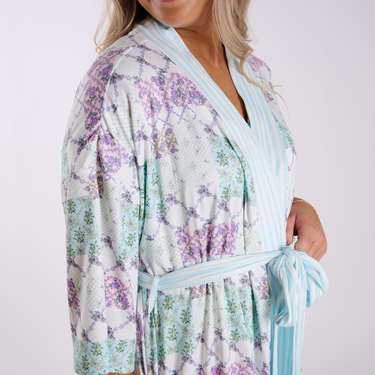 Floral patchwork robe close-up showing soft fabric, striped trim, and tie waist detail.