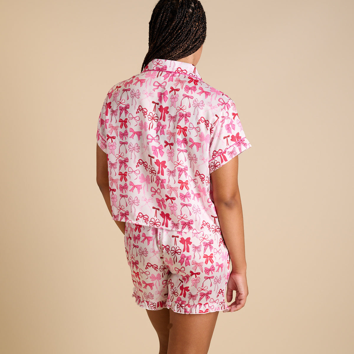Back view of pink bow print pajama shorts with ruffle hem and relaxed fit.