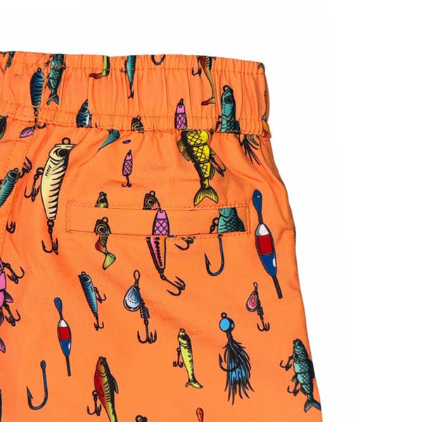 Close-up of orange youth swim shorts with fishing lure print, highlighting back pocket and elastic waistband.
