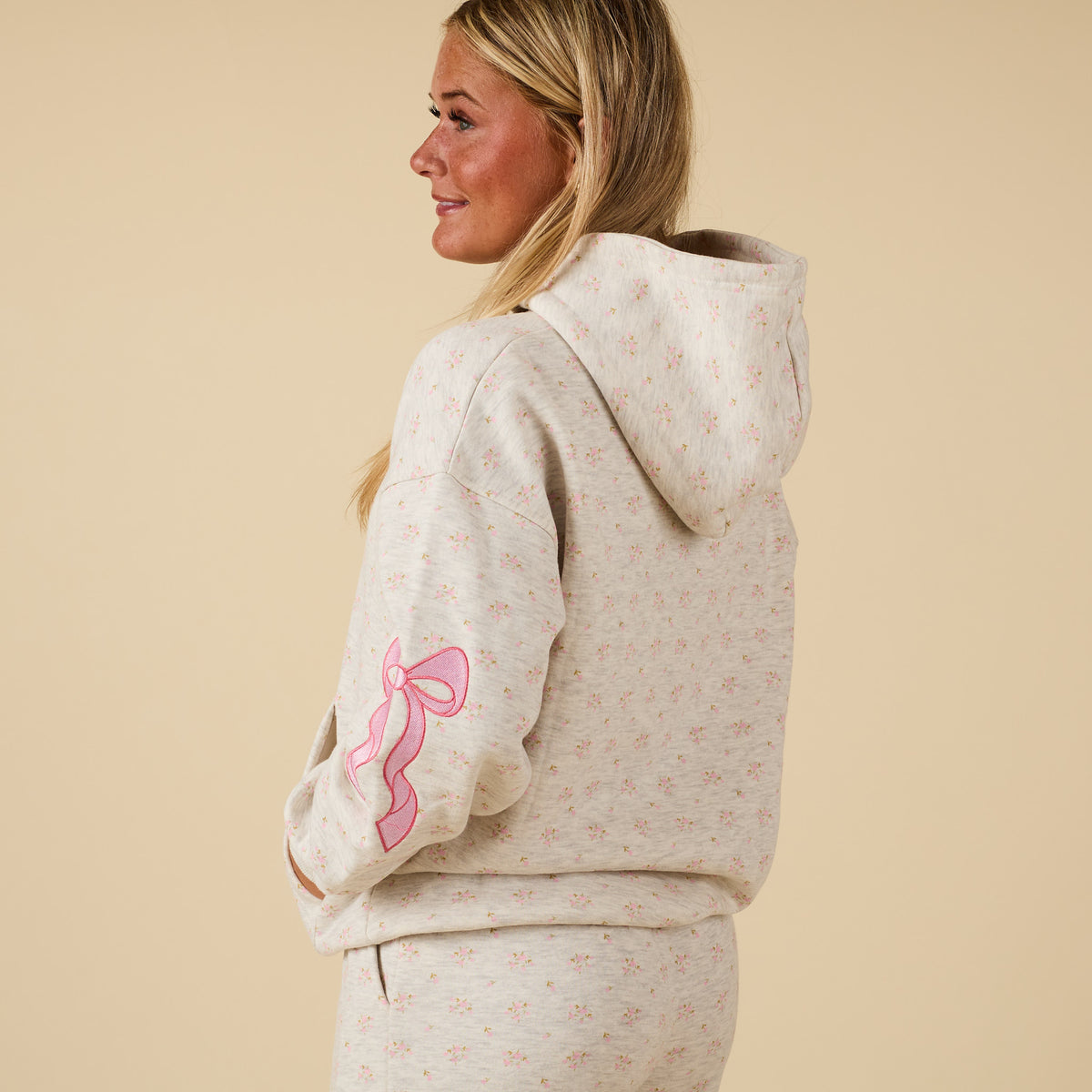 Back view of floral hoodie with pink bow embroidery on sleeve.