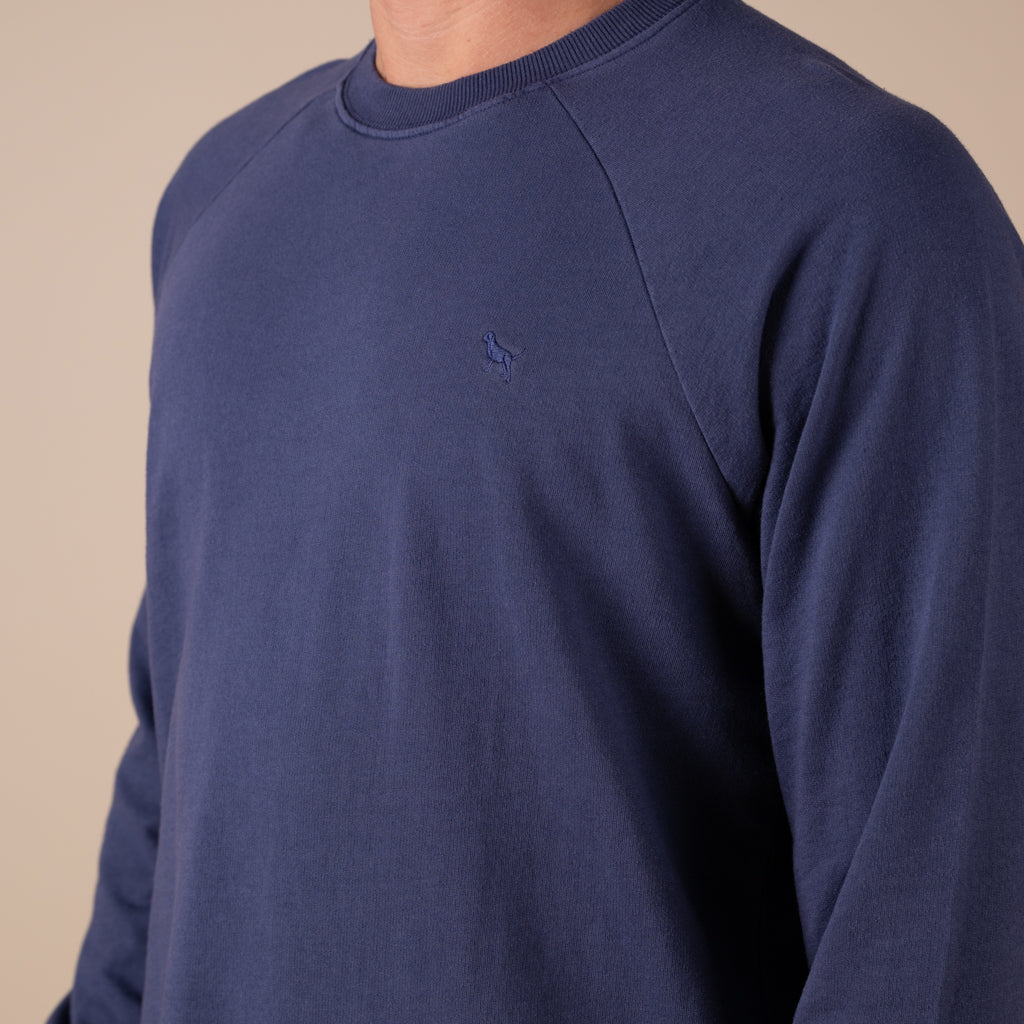 Navy blue sweater with a small logo on a beige background
