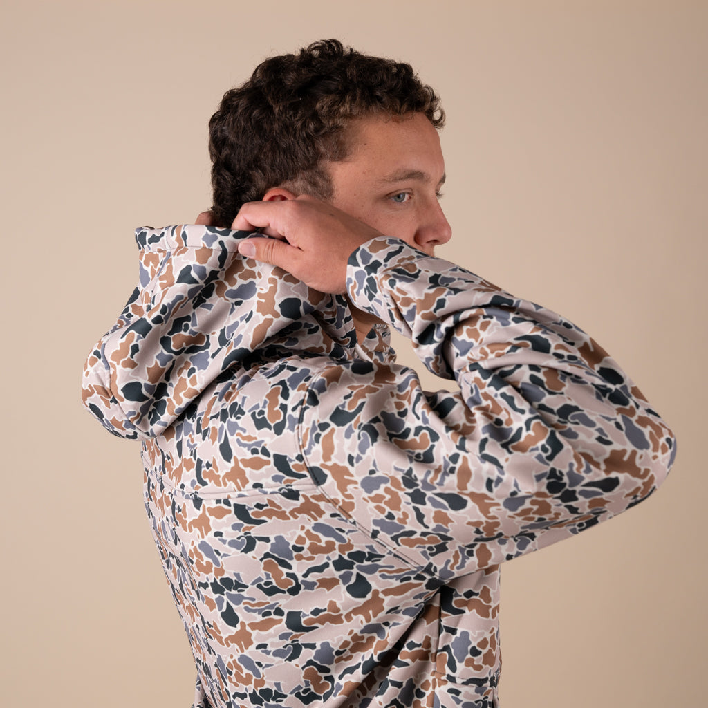 Person wearing a patterned jacket against a beige background